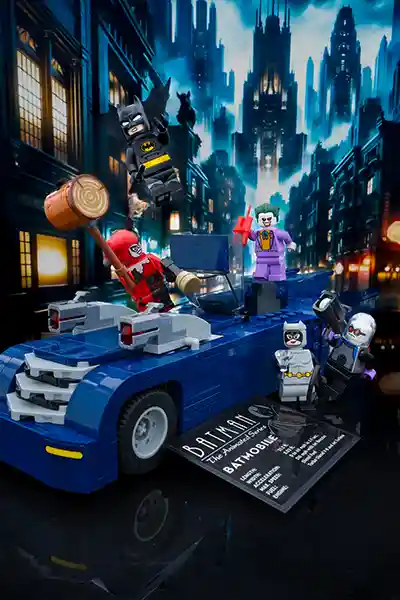 LEGO Batman from The Animated Series leaps into action against Harley Quinn, the Joker, Mr. Freeze, and Catwoman, all surrounding the iconic blue Batmobile build. The Gotham skyline looms dramatically in the background with Art Deco flair, capturing the essence of the animated classic.