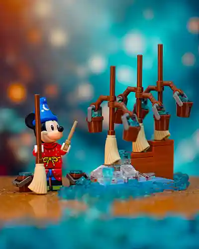 LEGO Sorcerer Mickey stands with a wand in hand, surrounded by enchanted broomsticks carrying water buckets, re-creating the iconic scene from Fantasia. Blue translucent LEGO bricks represent overflowing water against a dreamy, magical background.