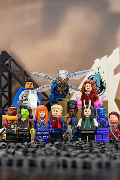 LEGO minifigures of Marvel's female superheroes—including Valkyrie, Gamora, Shuri, Scarlet Witch, Nebula, Wasp, and others—stand united in front of a crumbling Avengers compound, with Wasp flying above the group and powerful energy effects around them.