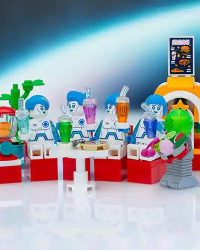 LEGO android nurses with blue hair enjoy colorful drinks and pizza in a futuristic space cafeteria, served by a green-headed alien robot waiter.