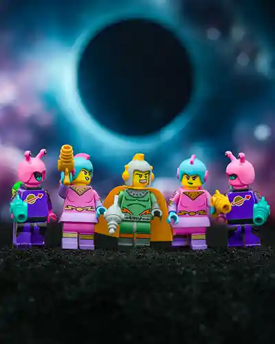 A vibrant team of six LEGO space minifigures stands united on a black alien terrain, with a glowing eclipse in the nebula-filled sky behind them. The team features two pink-suited aliens, two pink space warriors, a green-suited commander with an orange cape, and a blue-haired blaster-wielding fighter.