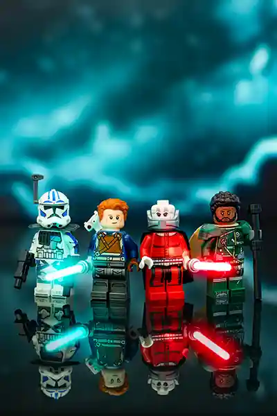 Four LEGO Star Wars minifigures stand in a dramatic teal-lit scene, reflected below them. From left to right: a blue-and-white Clone Trooper with a blaster and blue lightsaber, a Jedi with a droid companion on his back, a red Sith wielding a red lightsaber, and a rugged rebel warrior with a staff and green armor.