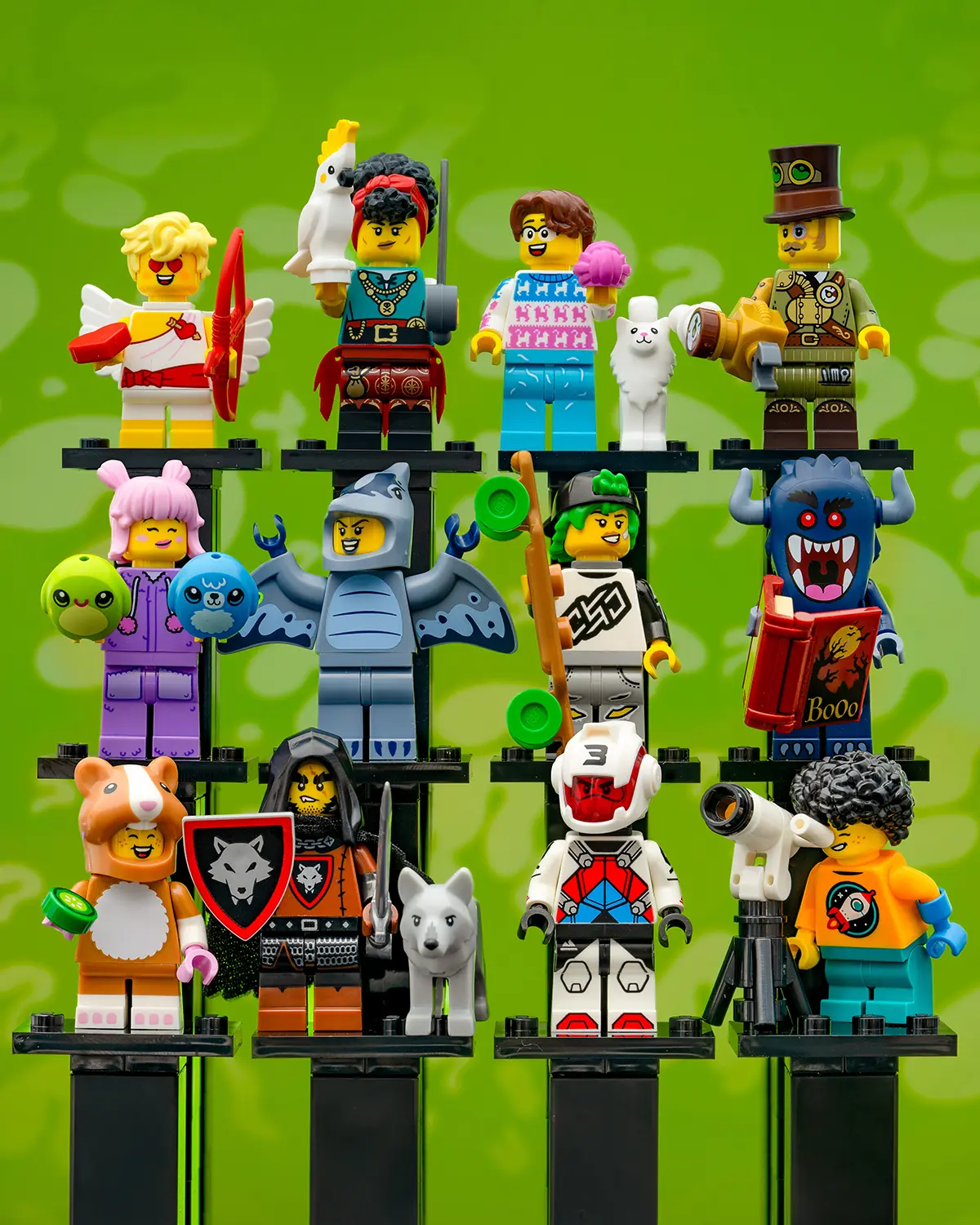 A full lineup of LEGO Collectible Minifigures Series 27 arranged in three rows against a green background. The characters include a cupid with a bow, a falconer, a llama-themed sweater guy, a steampunk explorer, a jellyfish girl, a bat knight, an orienteering scout, a book-reading monster, a hamster suit mascot, a wolf knight, a space racer, and a stargazing astronomer. Each minifigure stands on a black display base, showcasing the diverse and whimsical themes in this CMF series.