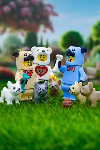 LEGO minifigures in dog and polar bear costumes playing with various LEGO bulldogs and pugs in a grassy park setting, with one holding a bone and another holding a toy, surrounded by colorful flowers and trees in the background. A LEGO poop piece sits humorously in the foreground
