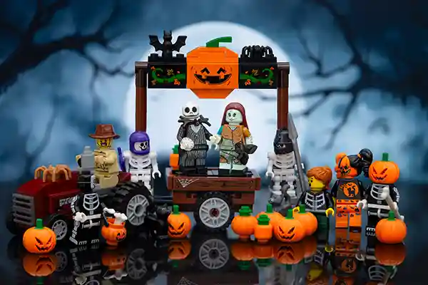 LEGO Halloween scene featuring Jack Skellington and Sally under a smiling pumpkin arch, surrounded by skeletons, monsters, pumpkins, and trick-or-treaters. A spooky moonlit forest sets the eerie backdrop.